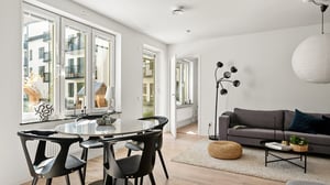 Inredd vardagsrum och matplats med soffa, runt matbord och stora fönster med ljusinsläpp