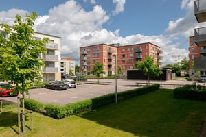 Flerbostadshus i vitt och rött med parkeringar och gräsmatta framför