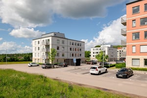 Flerbostadshus i vitt och rött med parkerade bilar på p-platser