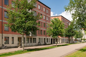 Flerbostadshus i  rött med träd mellan hus och lokalgata
