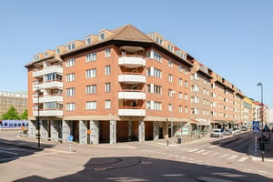 Flerfamiljshus med tegelfasad, balkonger omgiven av gator och torg under klar himmel