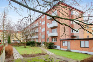 Flerfamiljshus i tegel med balkonger, omgivna av gräsmattor och träd