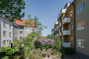 Innergård med bostadshus, balkonger och grönskande trädgård i solen