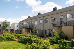 Flerbostadshus i radhuskänsla med grönska på baksidan av huset
