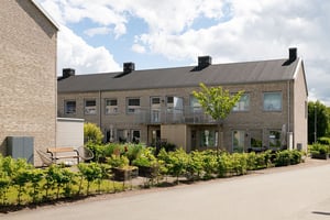 Flerbostadshus i radhuskänsla med grönska på baksidan av huset