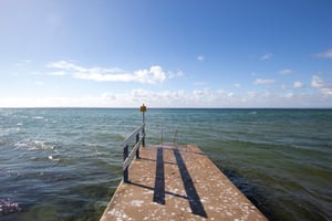 Brygga som sträcker sig ut i havet under en klar blå himmel