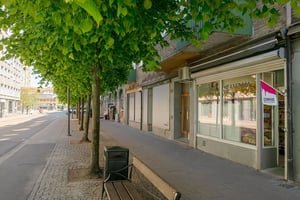 Flerbostadshus med butiker på bottenvåningen och trottoarer längs en gata