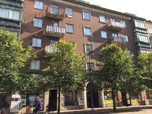 Flerbostadshus i tegel med balkonger och träd framför på gatan