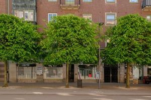 Flerbostadshus i tegel med butiker på bottenvåningen och trottoarer längs gata 