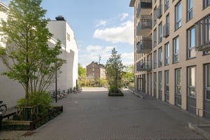 Flerbostadshus i ljus fasad med balkonger längs med stenbelagd gata