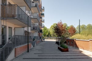 Nybyggnad med flerfamiljshus i tegel och ljusa fasader, längs stenbelagd gågata med planteringar