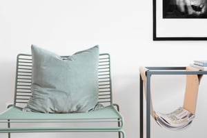 Lägenhet med grön stol, kudde, sidobord och inredningsdetaljer i ljus, modern stil