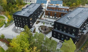 Flygfoto över moderna flerbostadshus med solpaneler och grön innergård