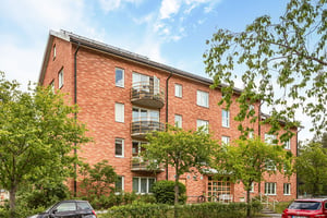 Flerbostadshus i tegel med balkonger mot grönområde