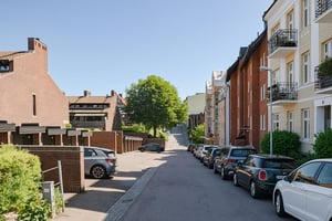 Gata med parkerade bilar längs vägen, och flerbostadshus till höger i bild och lägre bostadshus till vänster
