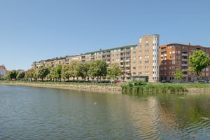 Flerbostadshus i tegelfasad med ljusa detaljer längs med vattenkanal