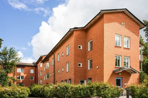 Flerbostadshus i tegel med grönska kring husen