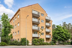 Flerbostadhus i tegel med balkonger och grönska kring husen
