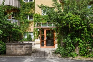 Entreport till flerbostadshus med grönska kring ingången