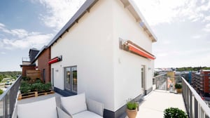 Balkong med sittgrupp och utsikt över bostadskvarter, vid ljus fasad och moderna fönster