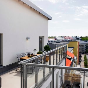 Balkong med bord och stolar vid modern lägenhet med utsikt över bostadshus