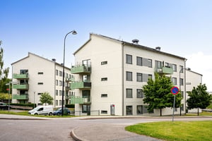 Flerbostadshus i ljus puts med gröna balkonger