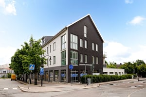 Flerbostadshus i ljus och mörk puts med lokal i entreplan