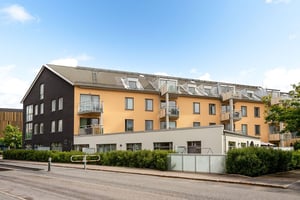 Flerbostadshus i mörk och gul puts med lägre del i ljus puts