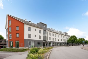 Flerbostadshus i ljus och röd puts med lokal i entreplan