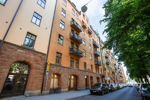Flerbostadshus i ljus puts och tegel med balkonger med smidesräcken