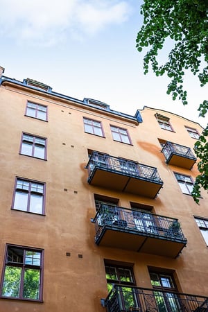 Flerbostadshus i ljus puts med balkonger med smidesräcken
