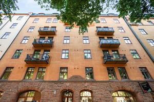 Flerbostadshus i ljus puts och tegel, med balkonger med smidesräcken