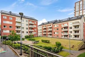 Grön innergård med sittplatser mellan flerbostadshus i puts och tegel