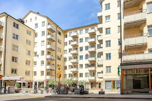 Flerbostadshus i ljus puts med torgliknande yta utanför porten