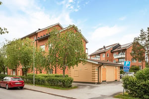 Förrådshuss coh träd framför flerbostadshus