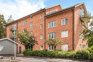 Flerbostadshus i tegel med grönskande kring huset