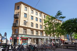 Hyresrättsfastighet i hörnet av lokalgata med parkerade cyklar i förgrunden