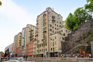 Hyresrättsfastigheter i olika nivåer längs lokalgata, och trappa i bergsvägg på sidan av huset