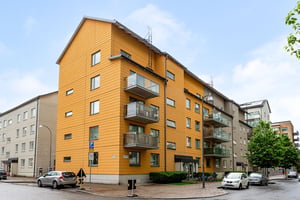 Hyresrättsfastighet med balkonger ut mot lokalgata, med parkerade bilar