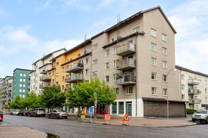 Hyresrättsfastighet med balkonger ut mot lokalgata, med parkerade bilar