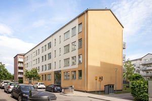 Hyresrättsfastighet med bilar parkerade längs lokalgata