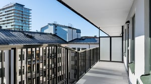 Balkong i en inflyttningsklar lägenhet med svart räcke och utsikt över flerfamiljshus