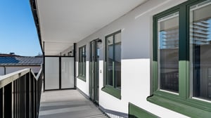 Inflyttningsklar lägenhet med balkong och grönfärgade fönster i ett modernt flerbostadshus
