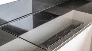 Inflyttningsklart kök med svart induktionshäll och bänkskiva i sten
