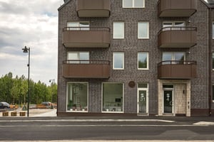 Flerfamiljshus med bruna balkonger och butikslokaler i bottenplan