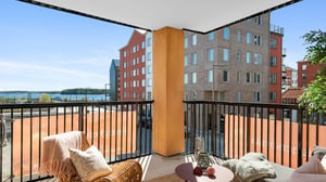 Balkong med sittgrupp och utsikt över moderna bostadshus och vatten