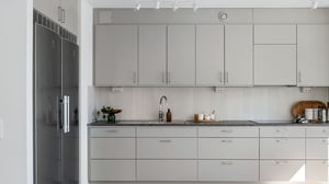 Modernt inflyttningsklart kök med ljusa skåp, rostfri kyl och stilren bänkskiva