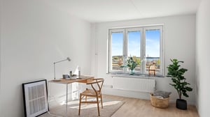 Inflyttningsklar lägenhet med ljusa väggar, stora fönster och möblerad arbetsplats i modern stil