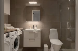 Modernt badrum med tvättmaskin, handfat, toalett och dusch