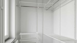 Vit klädkammare med öppna hyllor, trådkorgar och en stång för upphängning. Naturligt ljus från ett fönster till vänster